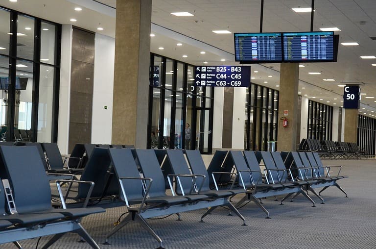 의자, 게이트 표지판, 항공편 디스플레이가 있으며 비어있는 공항 터미널